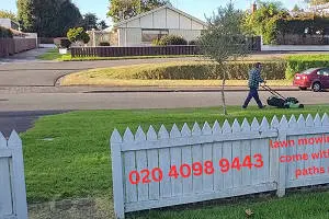 Gerard mowing lawn with white picket fence in Tauranga NZ